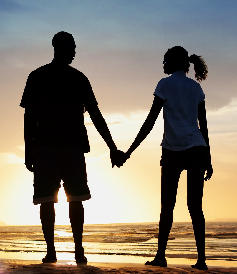 A silhouette of a couple holding hands on the beach